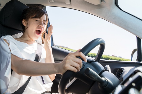 Drowsy driver lifting hand to stifle a yawn