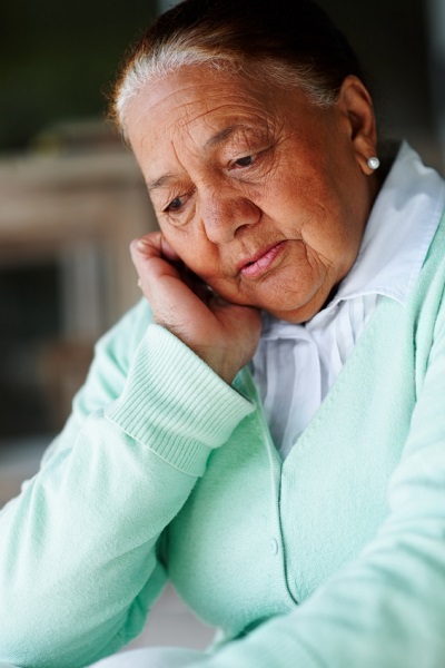Elderly woman cradling her head in one hand