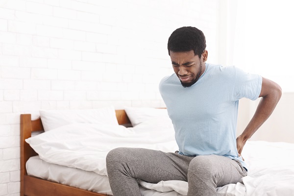 A man waking up in the morning grabbing his back because of pain caused by a latent car accident injury