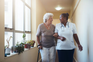 Portrait of smiling healthcare worker walking and talking with senior woman
